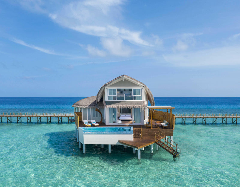 A duplex overwater villa at JW Marriott Maldives, curved roof and glass upper floor above the lagoon.