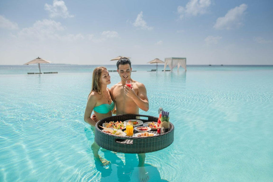 Couple enjoying a floating breakfast tray in their private pool villa, Maldives