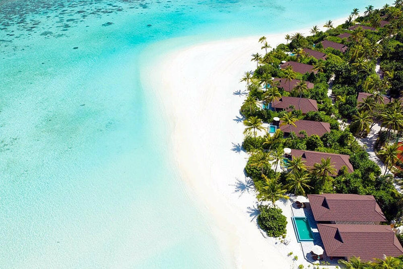 The Standard Huruvalhi from the air, villas among palms at the island tip beside a pale sandbank.