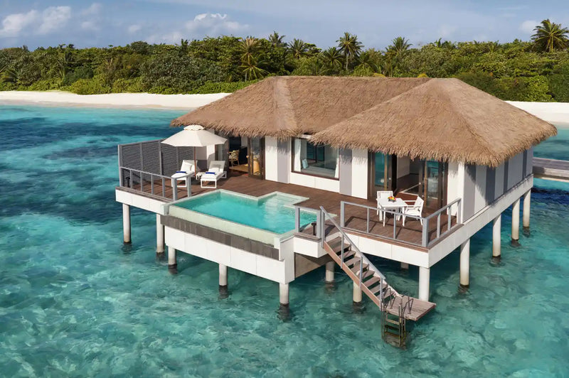 A water villa at Noku Maldives, plunge pool on the deck and timber steps down to the lagoon.