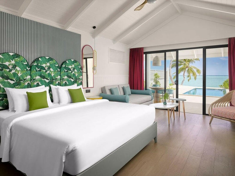 A pool villa bedroom at Villa Park Sun Island, a leaf print headboard and red curtains at the terrace doors