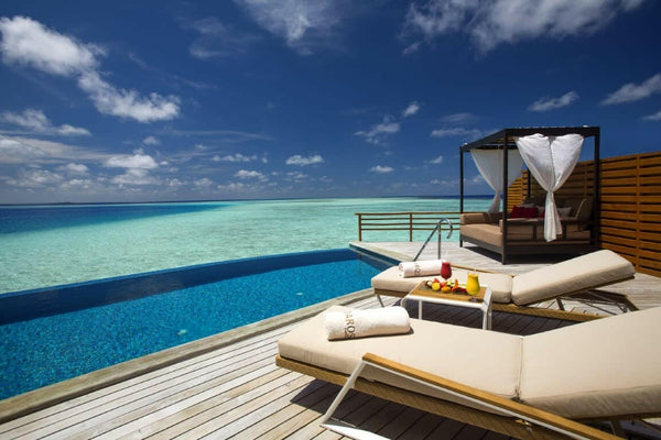 A water villa pool at Baros Maldives, a curtained daybed and loungers at the edge of the open sea.