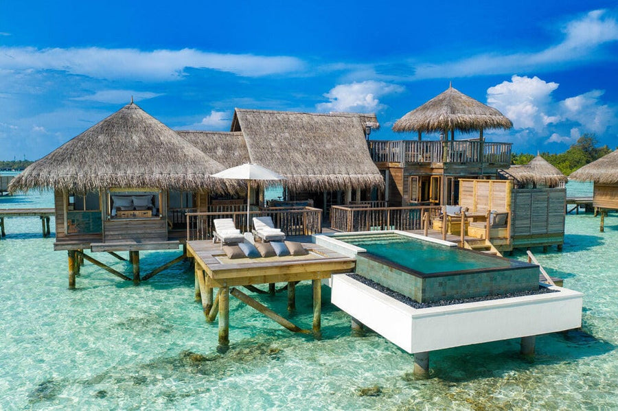 A Villa Suite with Pool at Gili Lankanfushi Maldives, on timber stilts with a dark infinity pool and loungers on the deck.