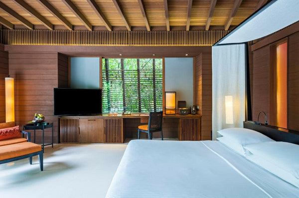 A villa bedroom at Park Hyatt Maldives Hadahaa, a writing desk and louvred shutters in a timber lined room
