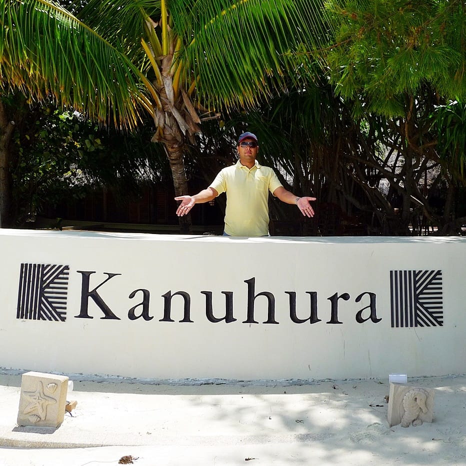 A visitor stands behind the old resort sign at Six Senses Kanuhura, from before it became a Six Senses.