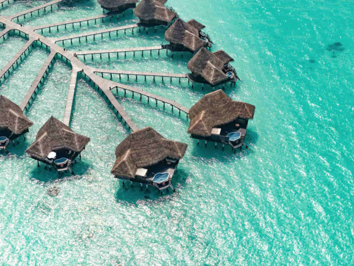 Lagoon villas fanned out along their walkway over bright turquoise shallows at Coco Palm Dhuni Kolhu
