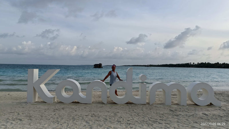Amosha, standing by the Kandima signage, on one of the islands beaches