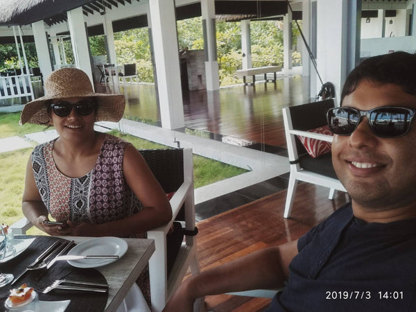 Two people at a lunch table in an open-sided timber restaurant at Noku Maldives