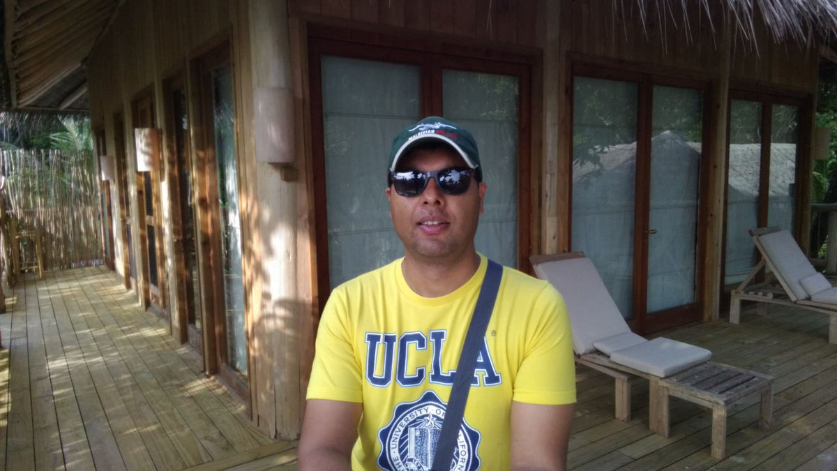A man in front of a timber villa with a shaded veranda and sun loungers at Soneva Fushi