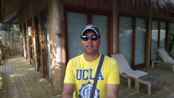 A man in front of a timber villa with a shaded veranda and sun loungers at Soneva Fushi