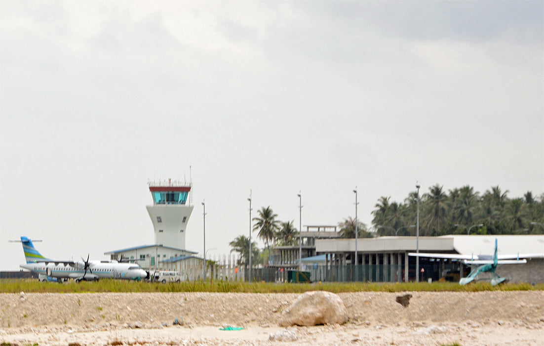 The control tower and terminal of Villa International Airport on Maamigili, with palm trees behind
