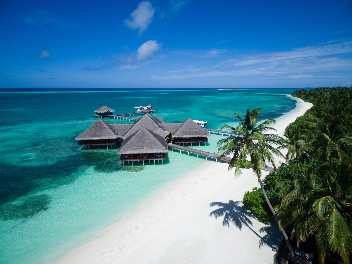Medhufushi Island Resort from the air, water villas above the lagoon beside the beach
