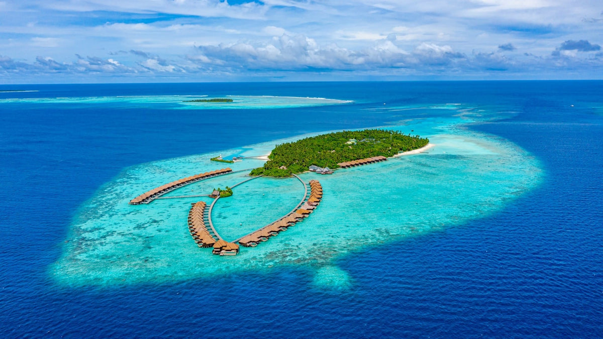 Ayada Maldives from the air, the wooded island and its curving lines of overwater villas