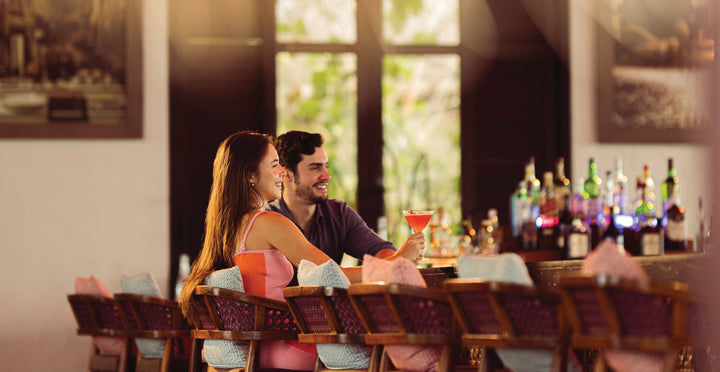 A couple sharing drinks at the bar at OBLU SELECT Lobigili, North Malé Atoll