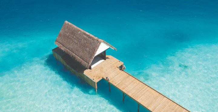 A thatched overwater pavilion at the end of a jetty at OBLU Xperience Ailafushi, seen from above