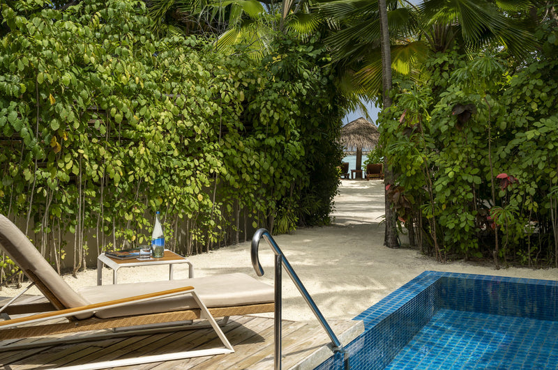 The private pool of a Baros Pool Villa at Baros Maldives, loungers on a sandy deck between tall tropical plants.
