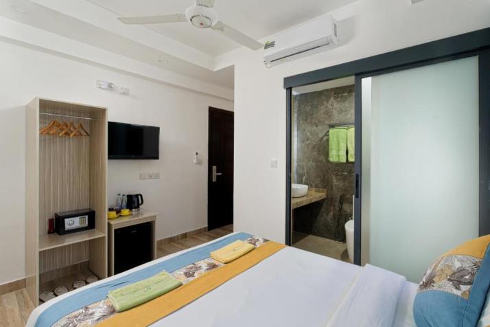 h78 Iru Hulhumalé, North Malé Atoll: Double Room with a double bed, an open wardrobe, a wall TV and a frosted glass door to the bathroom