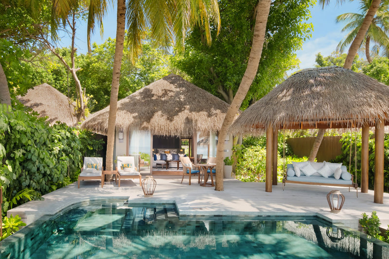 A Baros Suite with Private Pool at Baros Maldives, the pool in front of two thatched pavilions under palms.