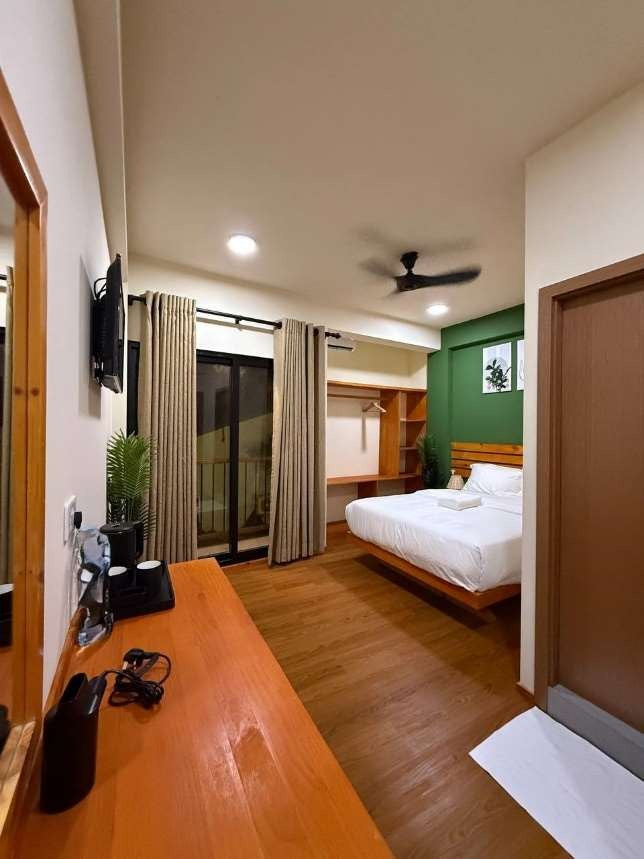 Ruka Maldives Dhiffushi, North Malé Atoll: Deluxe Room with a double bed, a long wooden desk and a glass door to the balcony