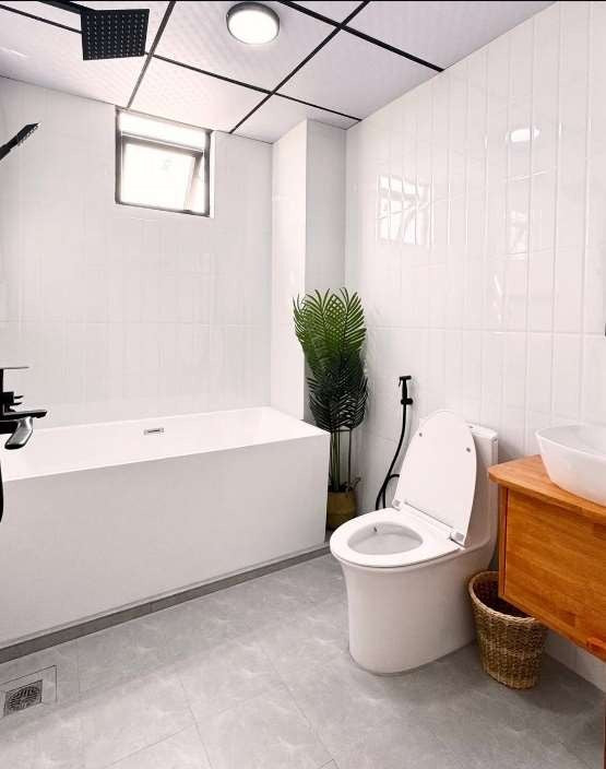 Ruka Maldives Dhiffushi, North Malé Atoll: white-tiled bathroom with a freestanding bathtub, a wooden vanity and a rain shower