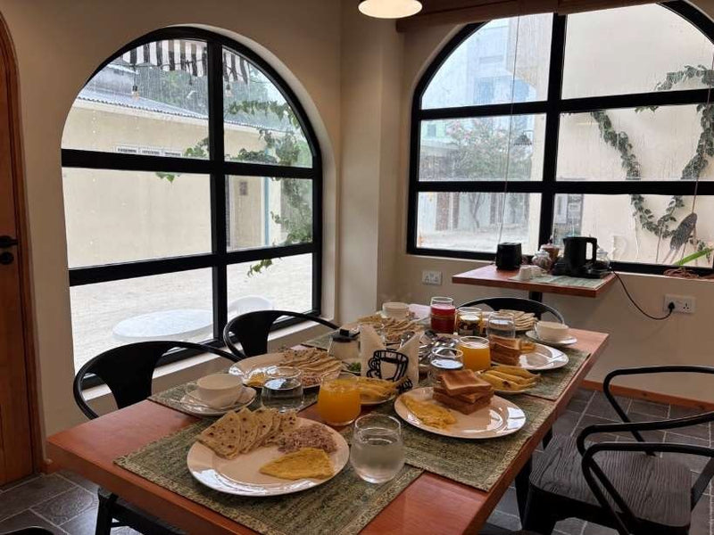 Ruka Maldives Dhiffushi, North Malé Atoll: breakfast plates on a table beside arched black-framed windows