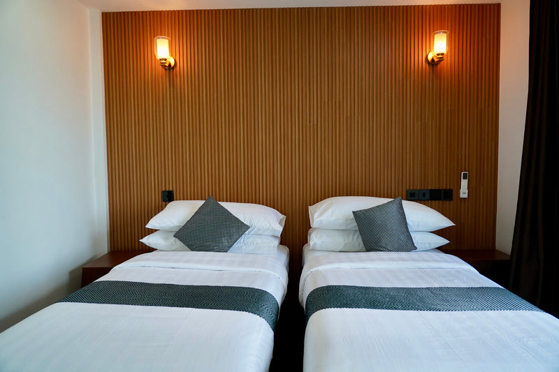 Twin room at Cozy Art Dhangethi with two single beds against a timber-panelled wall