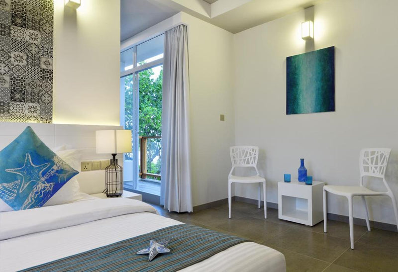 Room at Velana Beach Hotel with a glass door to a balcony with two chairs