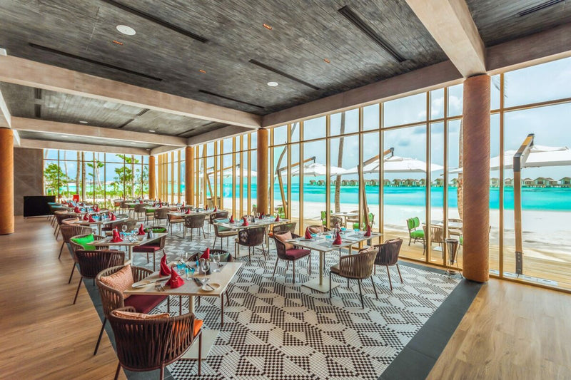 A restaurant at Hard Rock Hotel Maldives, glazed from floor to ceiling onto the beach and lagoon.