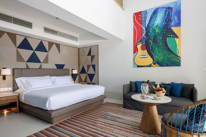 A bedroom in a Silver Family Suite at Hard Rock Hotel Maldives, guitar artwork above the sofa.