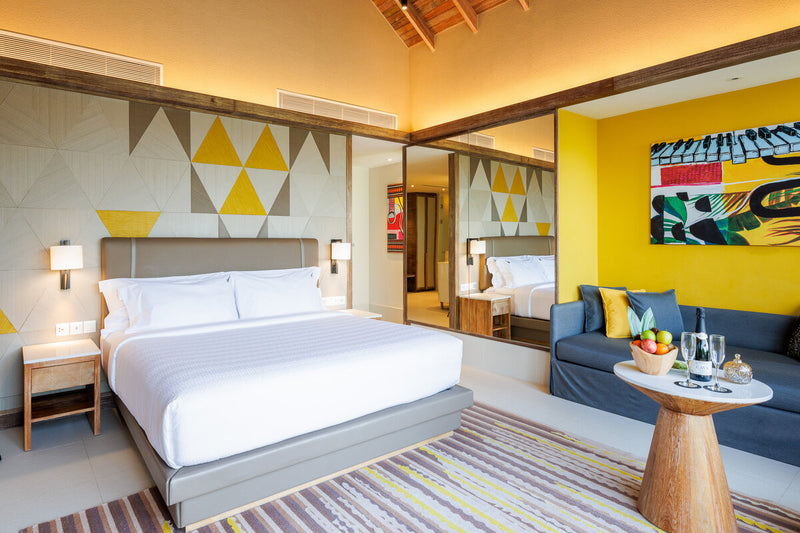 A Gold Beach Villa at Hard Rock Hotel Maldives, king bed against a patterned headboard wall.