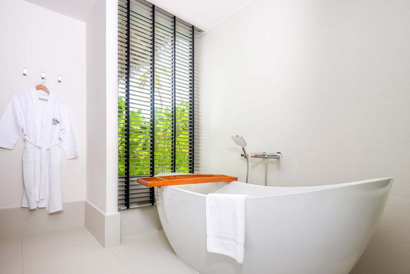 A villa bathroom at Hard Rock Hotel Maldives, a freestanding bath beside a louvred window.