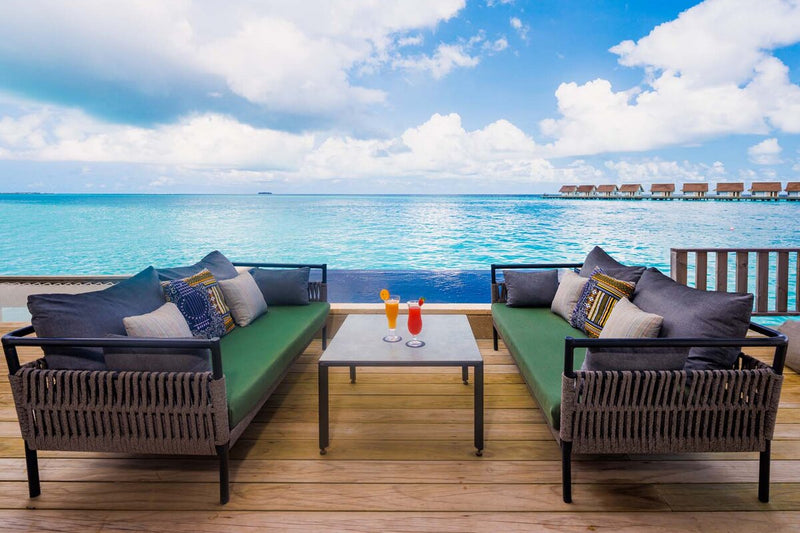 An overwater deck at Hard Rock Hotel Maldives, two sofas and a low table facing the lagoon.