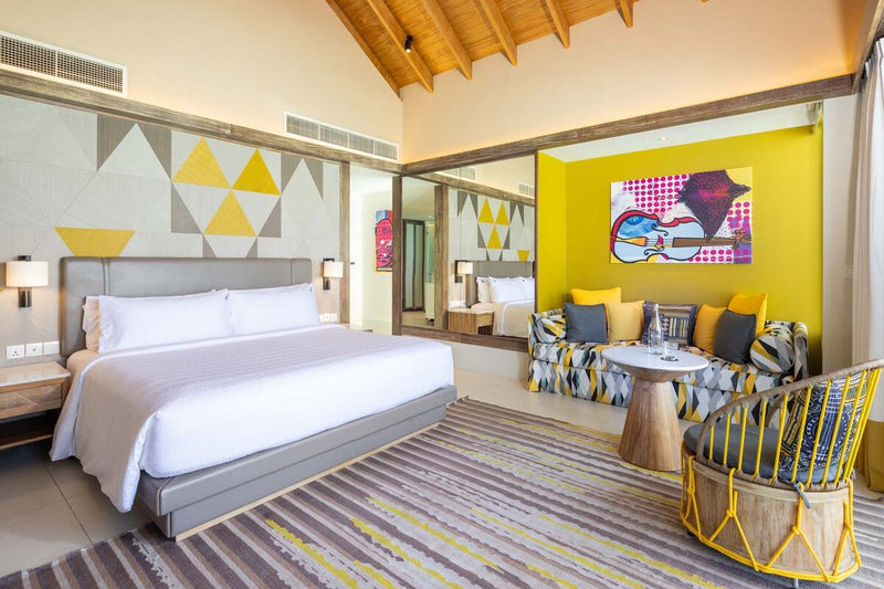 A bedroom at Hard Rock Hotel Maldives, a yellow feature wall and pop art above the bed.