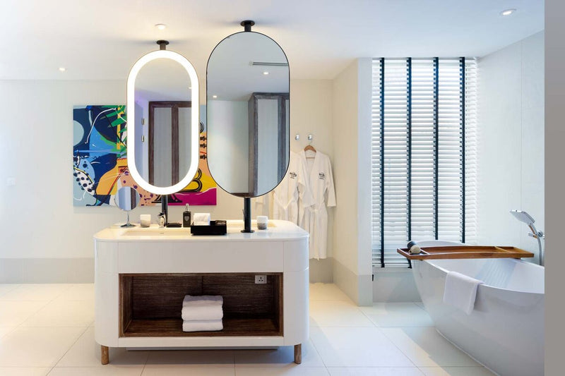 A villa bathroom at Hard Rock Hotel Maldives, twin oval mirrors above a long vanity.