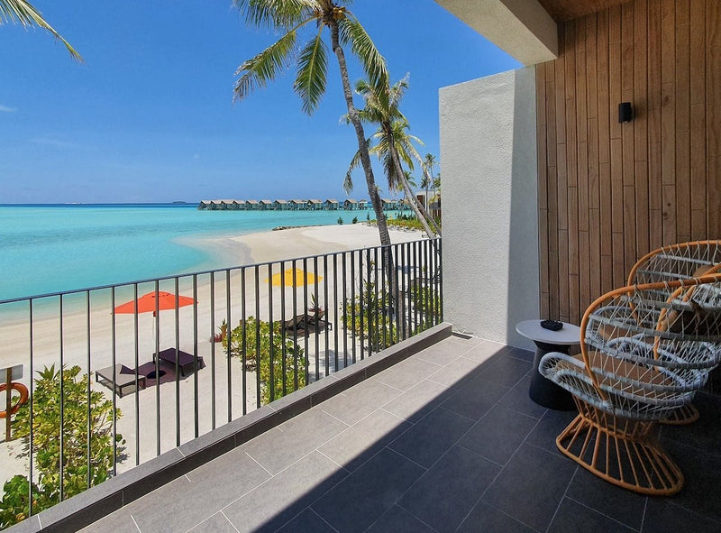 A villa balcony at Hard Rock Hotel Maldives, a hanging chair looking out at the overwater villas.