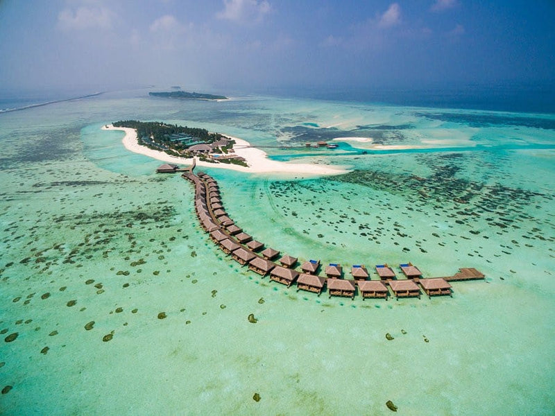 Cocoon Maldives from the air, the island and its overwater villa row.