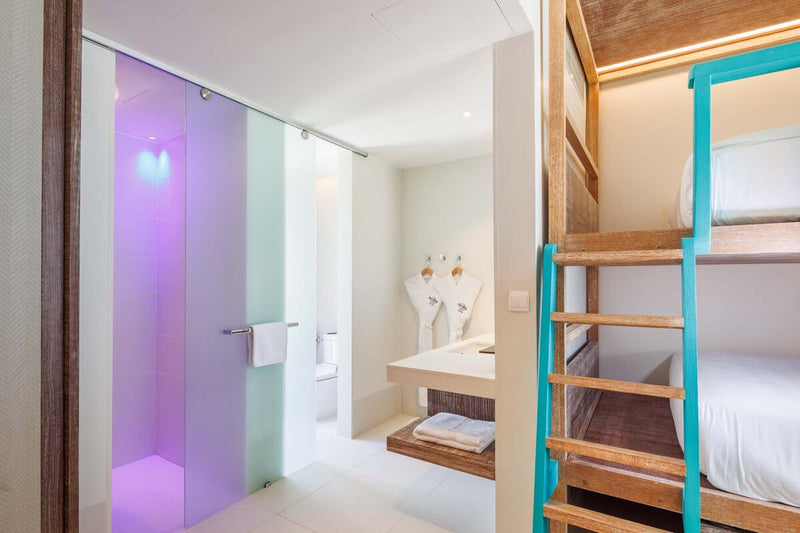 A villa bathroom at Hard Rock Hotel Maldives, a magenta lit shower beside the stairs.