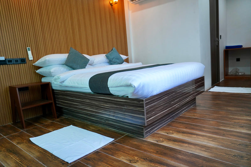 Double room at Cozy Art Dhangethi with timber panelling, a wooden bed and a window onto palms