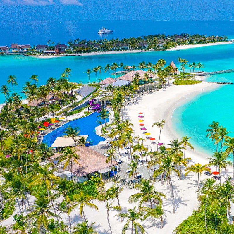 Hard Rock Hotel Maldives from the air, the main pool and beach parasols among the palms.