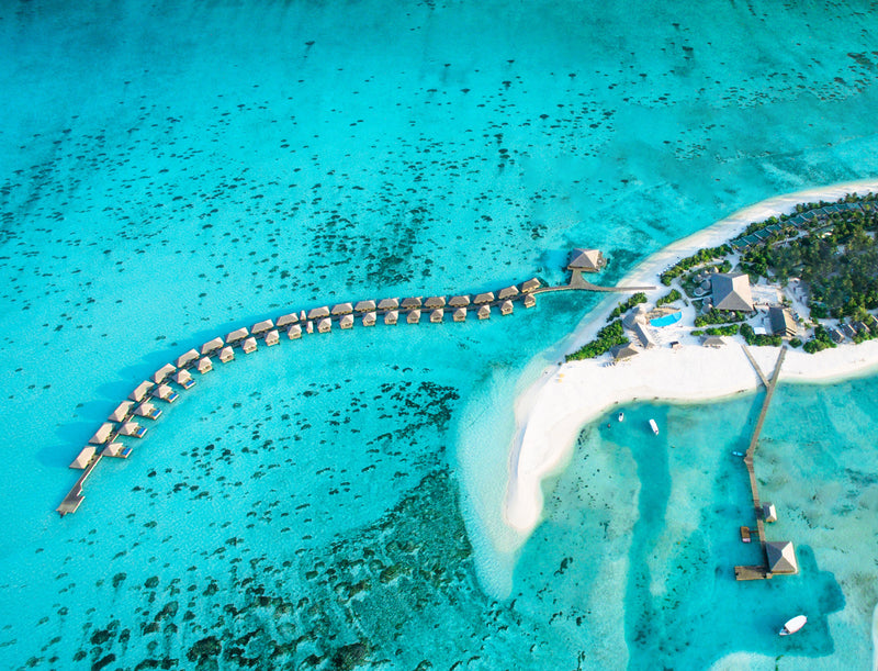Cocoon Maldives from the air, the overwater villas curving out from the island.