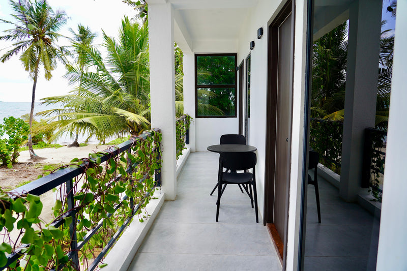 Private balcony at Cozy Art Dhangethi with a small table and chairs among palm leaves