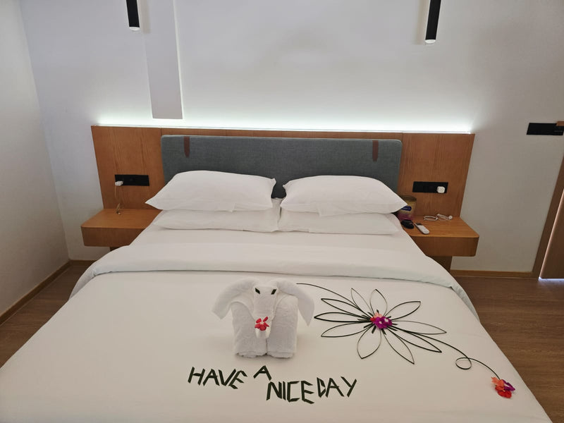 Double bed at Cozy Nest Fuvahmulah dressed with a towel decoration and a welcome message