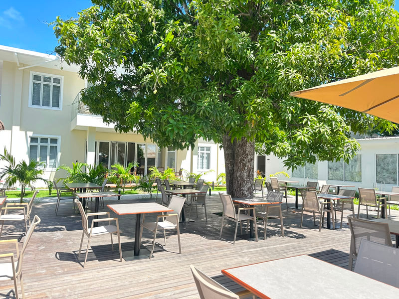Cozy Deck restaurant at Cozy Nest Fuvahmulah, tables and parasols under a large mango tree