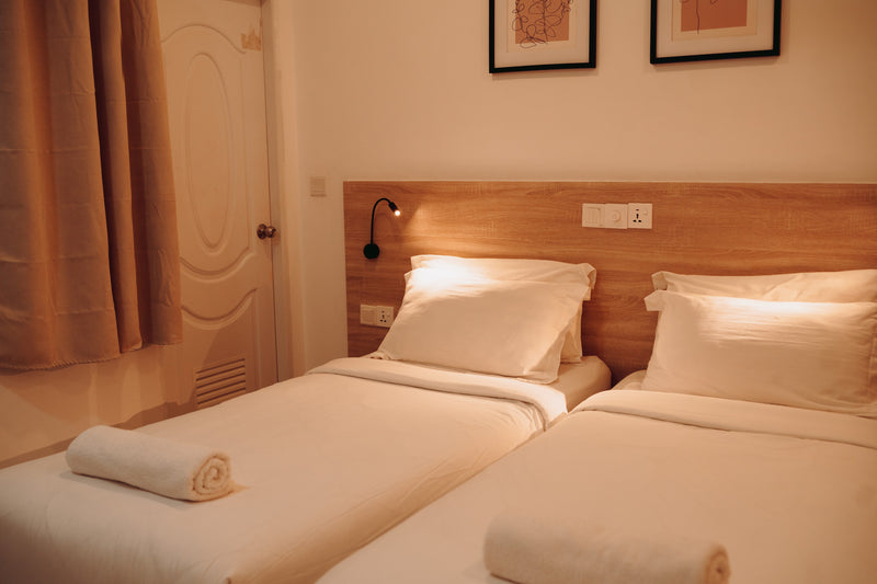 Room with two single beds, reading lamps and framed prints at Nala Island Village