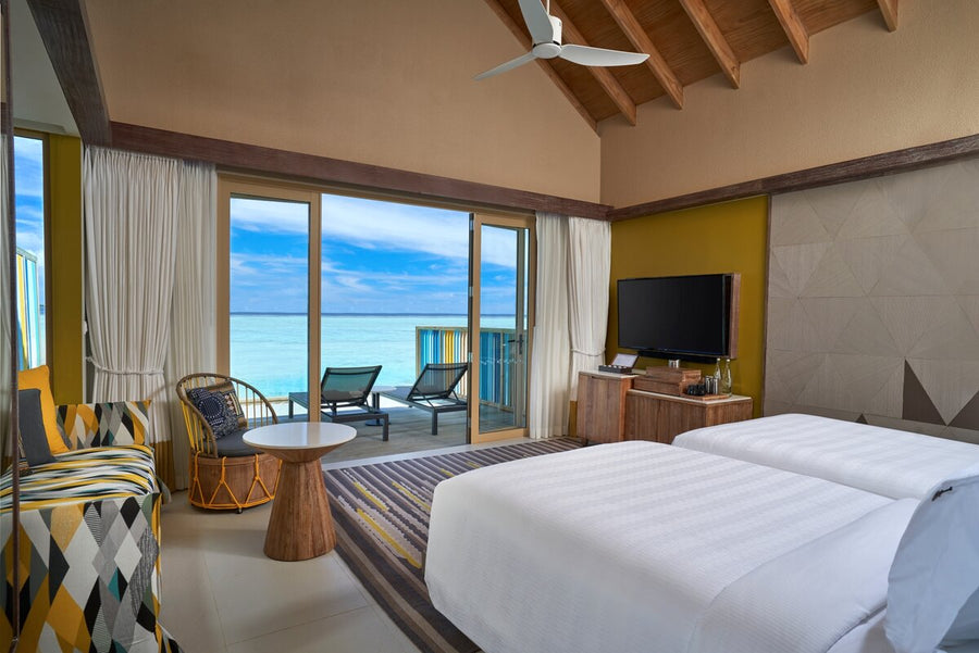 A Diamond Overwater Pool Villa at Hard Rock Hotel Maldives, the bedroom opening onto a deck above the lagoon.
