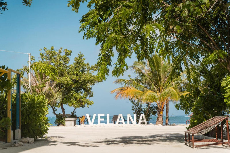 Velana sign on the sand under the trees on the Maafushi beach