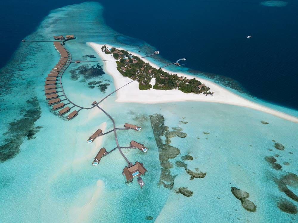 COMO Cocoa Island from the air, overwater villas branching off jetties into the shallows