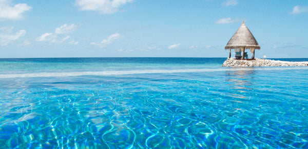 A thatched pavilion standing out in the lagoon at Taj Coral Reef Resort & Spa, Maldives.
