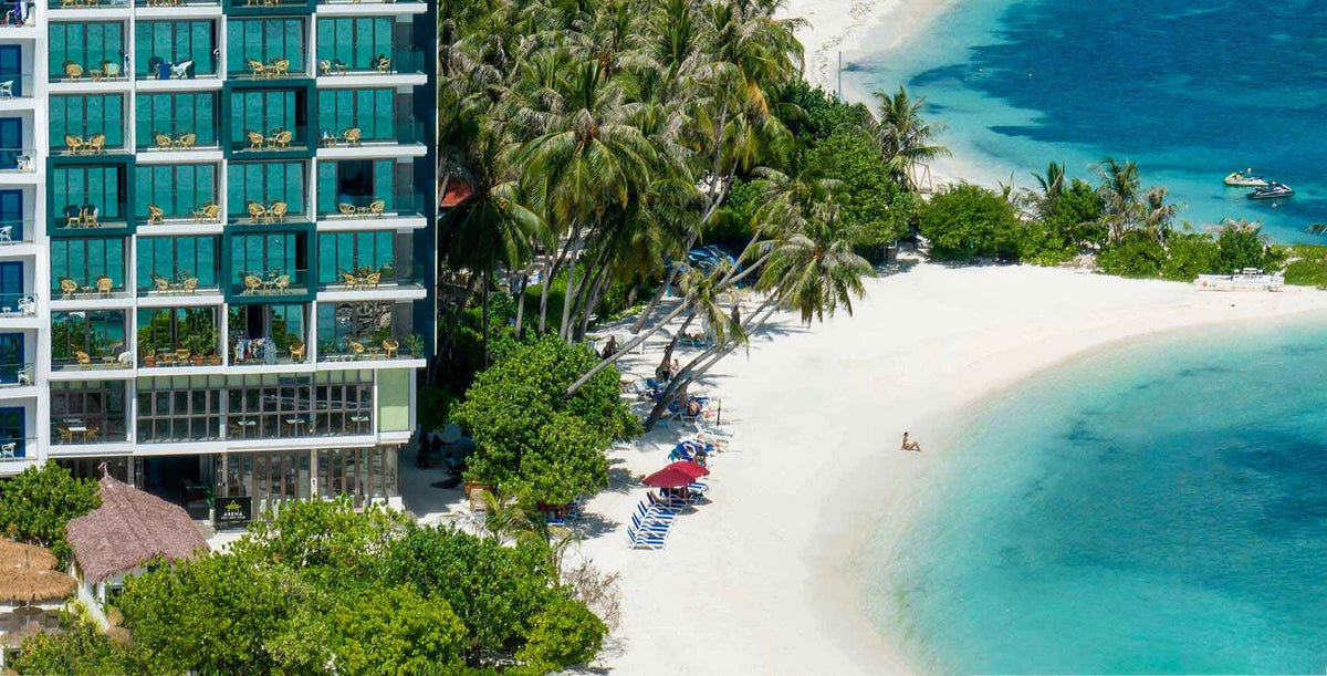 Arena Beach Hotel, a tall building with balconies beside the white sand beach on Maafushi