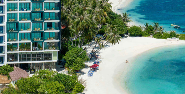 Arena Beach Hotel, a tall building with balconies beside the white sand beach on Maafushi
